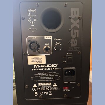 Zadní strana černého studiového monitoru. Je na něm vidět logo M-AUDIO a název modelu STUDIOPHILE BX5a DELUXE, v horní části je velký nápis BX5a DELU…