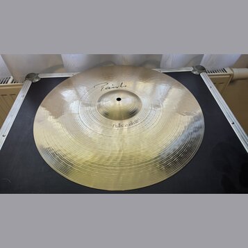 Kovový činel v zlatavé barvě s viditelným kovánívým povrchem. Na povrchu je nápis „Paiste“ a níže označení „Full Crash 18"“. Činel je položen na čern…