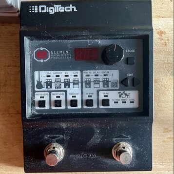 Černý efektový procesor s nápisem Digitech na horní hraně. Na předním panelu je uveden název ELEMENT GUITAR EFFECTS PROCESSOR a jsou umístěny ovládac…