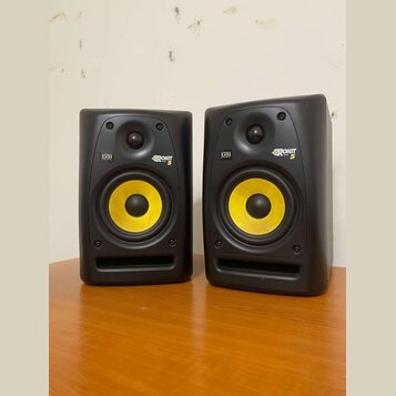 Dva černé studiové monitory s žlutými membránami basových reproduktorů. Na obou je vidět logo KRK a nápis ROKIT 5. Povrch krytů je matný, v dolní čás…