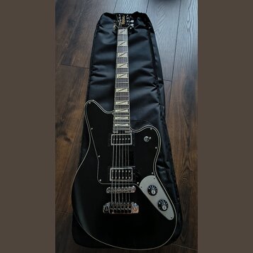 Černá elektrická kytara s hnědým hрифem a bílými vložkami na hmatníku, položená na černém obalu. Na hlavě je viditelné logo "Gretsch". Kytara má dva…