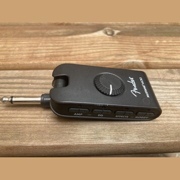 Černý kompaktní kytarový procesor Fender MUSTANG MICRO s integrovaným jackem. Na horní straně je umístěn jeden oválkový ovládací knoflík a nápisy Fen…