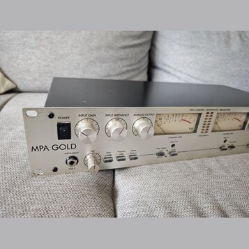 Stříbrný dvoukanálový mikrofonní předzesilovač s nápisem MPA GOLD. Přední panel obsahuje přepínač POWER, knoflíky INPUT GAIN a INPUT IMPEDANCE (označ…