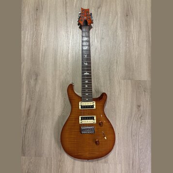 Elektrická kytara s tělem z plaménkového dřeva v hnědém odstínu a dvěma humbuckery s krémovými rámečky. Na hmatníku jsou vložky ve tvaru ptáků a na h…
