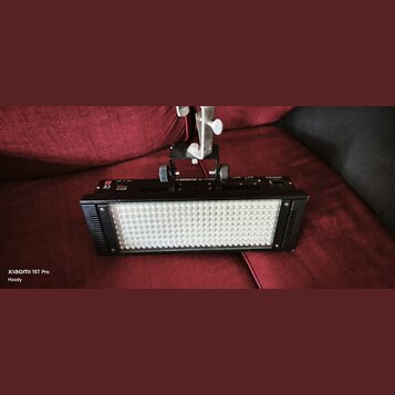 Černý obdélníkový LED panel s mřížkou bílých světelných bodů. Na horní hraně je nápis PUNCH IN a logo CE. Zařízení je připevněno k bílému kovovému st…