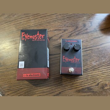 Na fotografii je kytarový efekt Eyemaster METAL DISTORTION značky tc electronic v originálním černém balení. Pedál má červenobílé provedení s dvěma o…