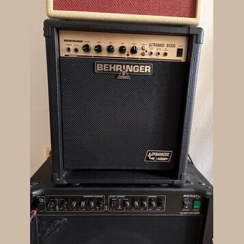 Černý basový kombo zesilovač značky BEHRINGER s modelem ULTRABASS BX300. Na horním ovládacím panelu jsou knofíky a přepínače s nápisy PASSIVE, ACTIVE…