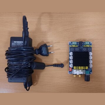 Černý síťový adaptér s napájecím kabelem a konektorem. Na štítku adaptéru je nápis FSP GROUP INC., Model: FSP099-AB AC, AC Input: 100-240V~ 1.5A, DC…