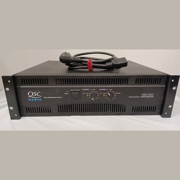Černý výkonový zesilovač v rackovém provedení s nápisem QSC AUDIO a označením DUAL MONAURAL SUPPLY. Na pravé straně je uveden model RMX 5050 a text P…
