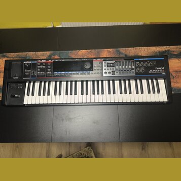 Černý syntetizátor s bílými a černými klávesami. Na pravé straně je bílý nápis Roland a pod ním model JUNO-60. Horní panel obsahuje různé ovládací pr…