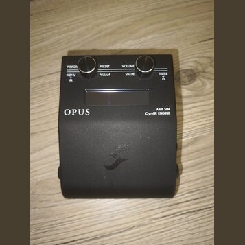 Černý kytarový efekt s nápisy OPUS a AMP SIM DynIR ENGINE. Zařízení má dva ovládací knoflíky a tlačítka s popisky PERFOR., PRESET, VOLUME, MENU, PARA…