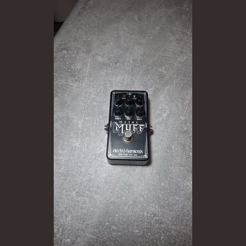 Černý kytarový efekt s nápisy METAL MUFF a electro-harmonix NEW YORK CITY, USA. Na horní straně jsou čtyři černé ovládací knoflíky a popisky TREBLE,…