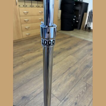 Detail chromovaného kovového stojanu. Na středové části je černý nápis 1000 HARDWARE SERIES. Povrch je lesklý, s viditelnými odrazy okolí.