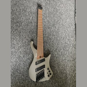 Stříbrná elektrická basa s šesti strunami a hnědým hmatníkem. Na korpusu je viditelné logo Ibanez. Nástroj má černý hardware a tři ovládací knoflíky…