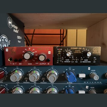 Fotografie zachycuje dva rackové audio procesory umístěné nad mixovací deskou. Levý červený přístroj nese nápisy PRE 73 Jr, GAIN, SIGNAL a OUTPUT. Pr…