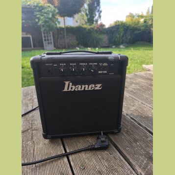 Černý kytarový kombo zesilovač s logem Ibanez na přední mřížce. Na ovládacím panelu jsou nápisy INPUT, DIST., GAIN, BASS, TREBLE, VOLUME, AUX IN, HEA…
