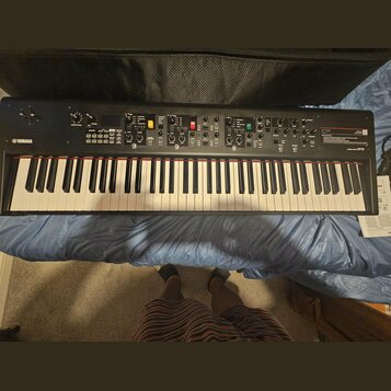 Černý digitální klavír značky YAMAHA. Na pravé straně panelu je nápis Stage Piano CP73 a červený štítek s textem CP. Nástroj má bílé a černé klávesy,…