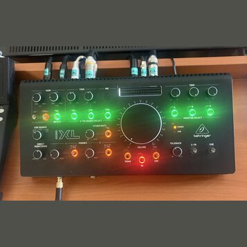 Černý audio rozhraní s ovládacím panelem, na kterém je bílé logo behringer. Zařízení obsahuje několik otočných potenciometrů pro GAIN, TRIM a VOLUME,…