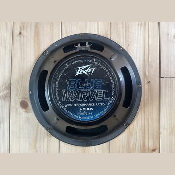 Černý kruhový reproduktor s kovovým rámem. Na středovém krytu je bílé logo Peavey a velký modrý nápis BLUE MARVEL. Dole je uveden text PRO PERFORMANC…