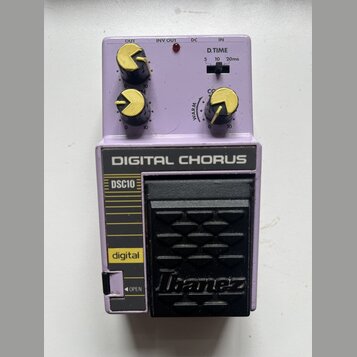 Fialový efekt pedál s nápisem DIGITAL CHORUS a označením DSC10. Na spodní části je černý stupňovací spínač s logem Ibanez. Horní panel obsahuje tři ž…