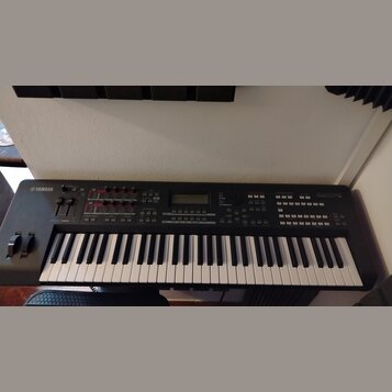 Černý digitální klavír s bílými a černými klávesami. Na levé straně je bílé logo YAMAHA a vpravo nápis MOX8. Horní panel obsahuje displej, několik po…