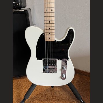 Bílá elektrická kytara typu Telecaster s černým plechtrátem a hnedým javorovým hmatníkem. Nástroj má chromovaný most s integrovaným snímačem a ovláda…