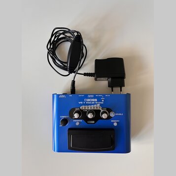 Modrý efektový pedál s nápisem BOSS VE-1 Vocal Echo. Zařízení má ovládací knoflíky označené LEVEL, TONE a TYPE, přepínače ENHANCE, DOUBLE a MEMORY or…
