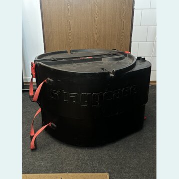 Černý plastový přepravní kufr s červenými popruhy. Na přední straně je vyembasovaný nápis staggcase. Povrch vykazuje běžné známky opotřebení v podobě…