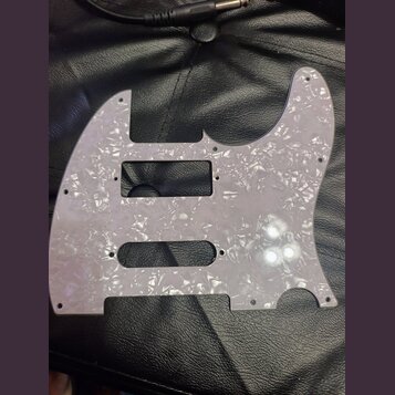 Světle šedý pickguard s perleťovým vzorem pro elektrickou kytaru. Je vyroben z plastového materiálu a obsahuje výřezy pro snímače a ovládací prvky. P…