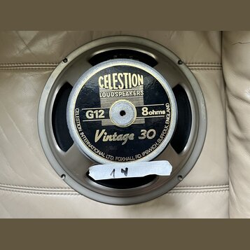 Kruhový reproduktor s kovovým rámem v šedé barvě. Na černém středovém krytu je zlatý nápis CELESTION LOUDSPEAKERS, G12, 8ohms a Vintage 30. Po obvodu…