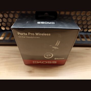 Černá kartonová krabice s nápisy Porta Pro Wireless a On-Ear Headphones. Na horní části je zrcadlově otočené logo KOSS a v dolní červené části nápis…