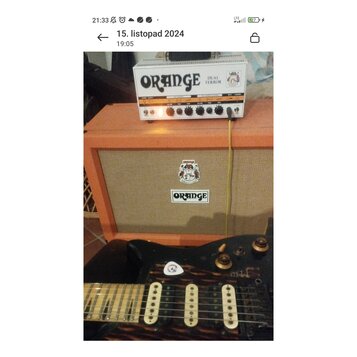Bílý kytarový zesilovač s nápisy ORANGE a DUAL TERROR stojí na oranžovém kytarovém boxu. Box má na přední síťce logo ORANGE a nad ním dekorativní nál…