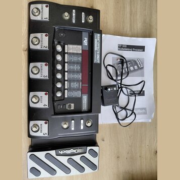 Černý multiefektový procesor s pět vệti spínacími pedály označenými jako COMPRESSOR, DISTORTION, CHORUS/FX, DELAY a REVERB. Na horní části je nápis R…