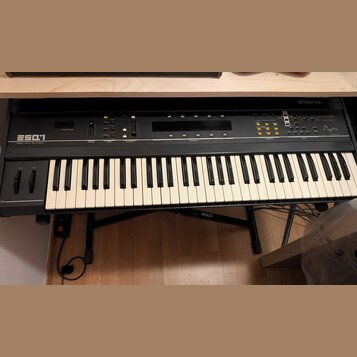 Černý syntetizátor s bílými a černými klávesami. Na levé straně je nápis ESD1 Digital Wave Synthesizer a v pravém horním rohu logo ensoniq. Přístroj…