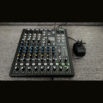 Černý mixážní pult s bílými a barevnými popisky. Na přístroji je viditelné logo PROXTON s označením modelu PRO-10.4+. K mixážní pultu je připojen čer…