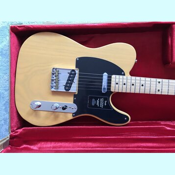 Světlé elektrické kytary typu Telecaster v tvrdém kufru s červeným polstrováním. Nástroj má světlý dřevěný povrch, černý pickguard a javorový hmatník…