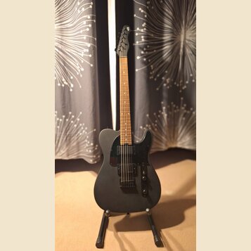 Kytara s matně černým tělem a hnedým hmatníkem, umístěná na stojanu. Nástroj má černý plech a dva humbuckery. Na hlavě kytary je viditelné logo, kter…