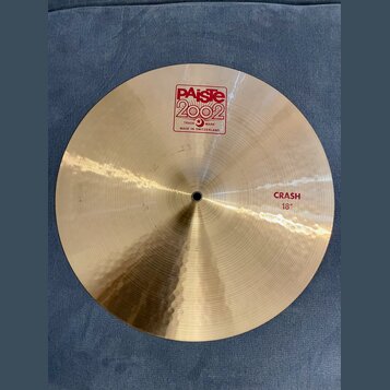 Zlatavý kovový činel s viditelným rýhováním povrchu. Na horní části je červené logo PAiste 2002 s nápisy TRADE MARK a MADE IN SWITZERLAND. V pravé čá…