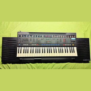 Černý digitální klavír s bílými a černými klávesami. Na ovládacím panelu je vlevo nápis YAMAHA PSR-4500 a vpravo dole na šasi nápis DASSYSTEM. Nástro…