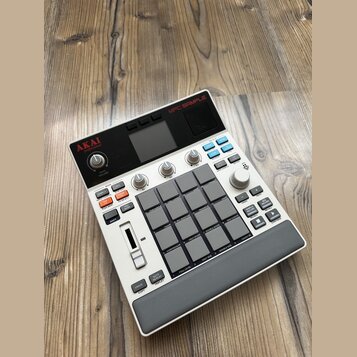 Světle šedý sampler s názvem MPC SAMPLE. Zařízení obsahuje 16 gumových padů, několik ovládacích knoflíků a řadu tlačítek s různými popisky, včetně lo…