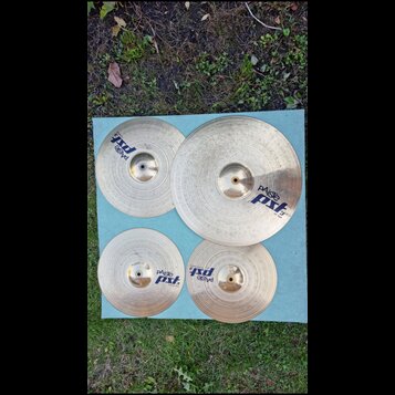 Sada čtyř mosazných činelů značky Paiste z řady pst 3. Na činelech jsou viditelné nápisy paiste a pst 3, přičemž u největšího je uveden text 20 RIDE.…