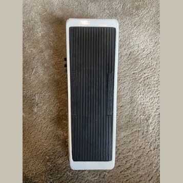Bílý efekt pedál s černou žebrovanou gumovou plochou. Na gumové části jsou svisle vyrazeny nápisy INSTRUMENT a AMPLIFIER. Povrch bílého rámu vykazuje…