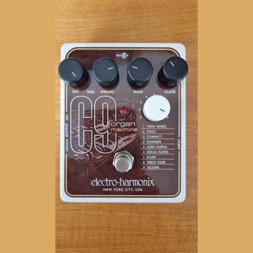 Hnědý kytarový efekt s bílým rámem a nápisem electro-harmonix NEW YORK CITY, USA. Na horní straně jsou čtyři černé ovládací knoflíky s popisky DRY, V…