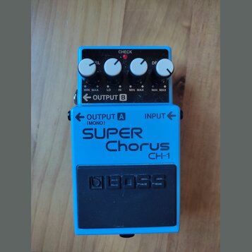 Modrý kytarový efekt s nápisy SUPER Chorus a CH-1. Na spodní části je černý gumový pedal s vyraženým logem BOSS. Horní panel obsahuje čtyři bílé otoč…