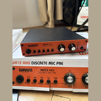 Oranžový mikrofonní předzesilovač s černým vrchem a čelním panelem. Na přístroji i na přiložené krabici je nápis WARM AUDIO WA12 MKII DISCRETE MIC PR…