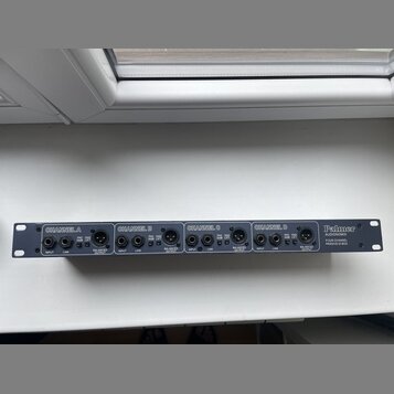 Černá racková DI box s čtyřmi kanály. Na přední straně jsou nápisy CHANNEL A, CHANNEL B, CHANNEL C a CHANNEL D, u každého z nich jsou vstupy INPUT, L…