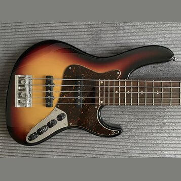 Elektrická basová kytara s korpusem v barevném přechodu od žluté přes oranžovou k hnědé a černé. Nástroj má tmavě hnědý pickguard s texturou želvy a…