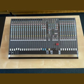 Šedý mixovací pult s velkým množstvím potenciometrů, posuvníků a vstupních konektorů. Na horní části je vidět bílý nápis ALLEN&HEATH a označení model…