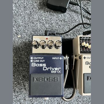 Modrý efekt pedál značky BOSS s názvem Bass Driver BB-1X. Horní část je stříbrná a obsahuje čtyři ovládací knoflíky, červenou kontrolku s nápisem CHE…