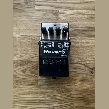 Kytarový efekt reverb v černé barvě s kovovým šasi. Na horní části jsou tři ovládací knoflíky a nápisy CHECK, MODULATE, SPRING, PLATE, HALL, ROOM, SH…